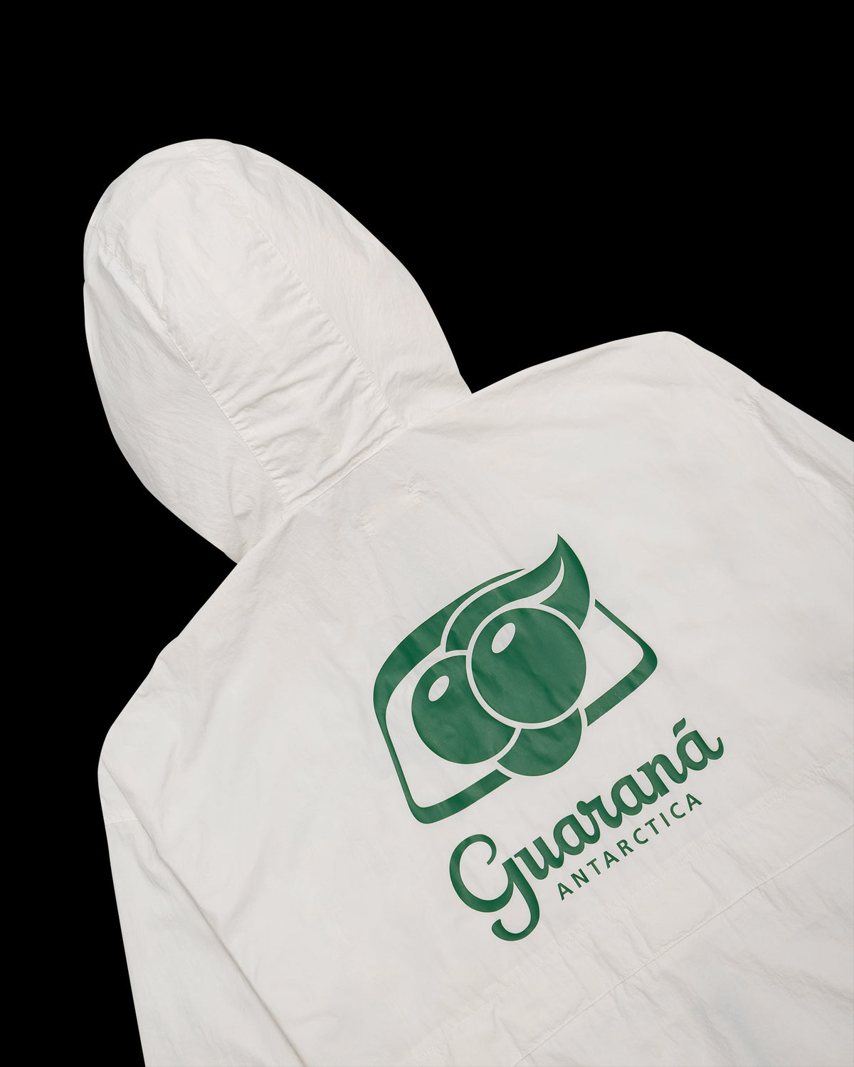 Laydown detalhe de costas da Jaqueta Wind Kiji Studio para Guaraná Antarctica, na cor off white com transfer 'Guaraná Antarctica' em verde.