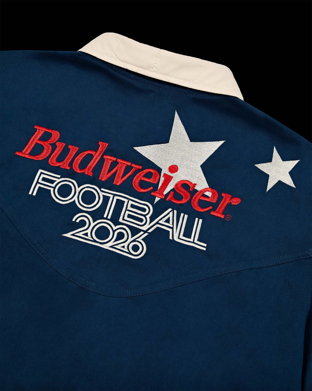Detalhe da Jaqueta Worker Kiji Studio para Budweiser Copa do Mundo 2026, na cor azul e bordado nas costas.