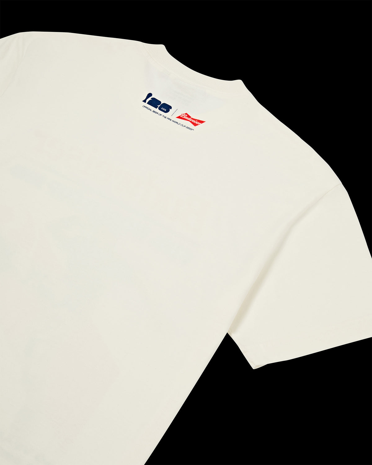 Laydown de costas da T-Shirt Heavy Kiji Studio para Budweiser Copa do Mundo 2026, na cor off white com detalhe em silk azul e vermelho.